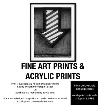 Illuminated Geometric Down Arrow on Textured Concrete Wall Black and White Print