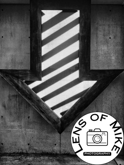 Illuminated Geometric Down Arrow on Textured Concrete Wall Black and White Print